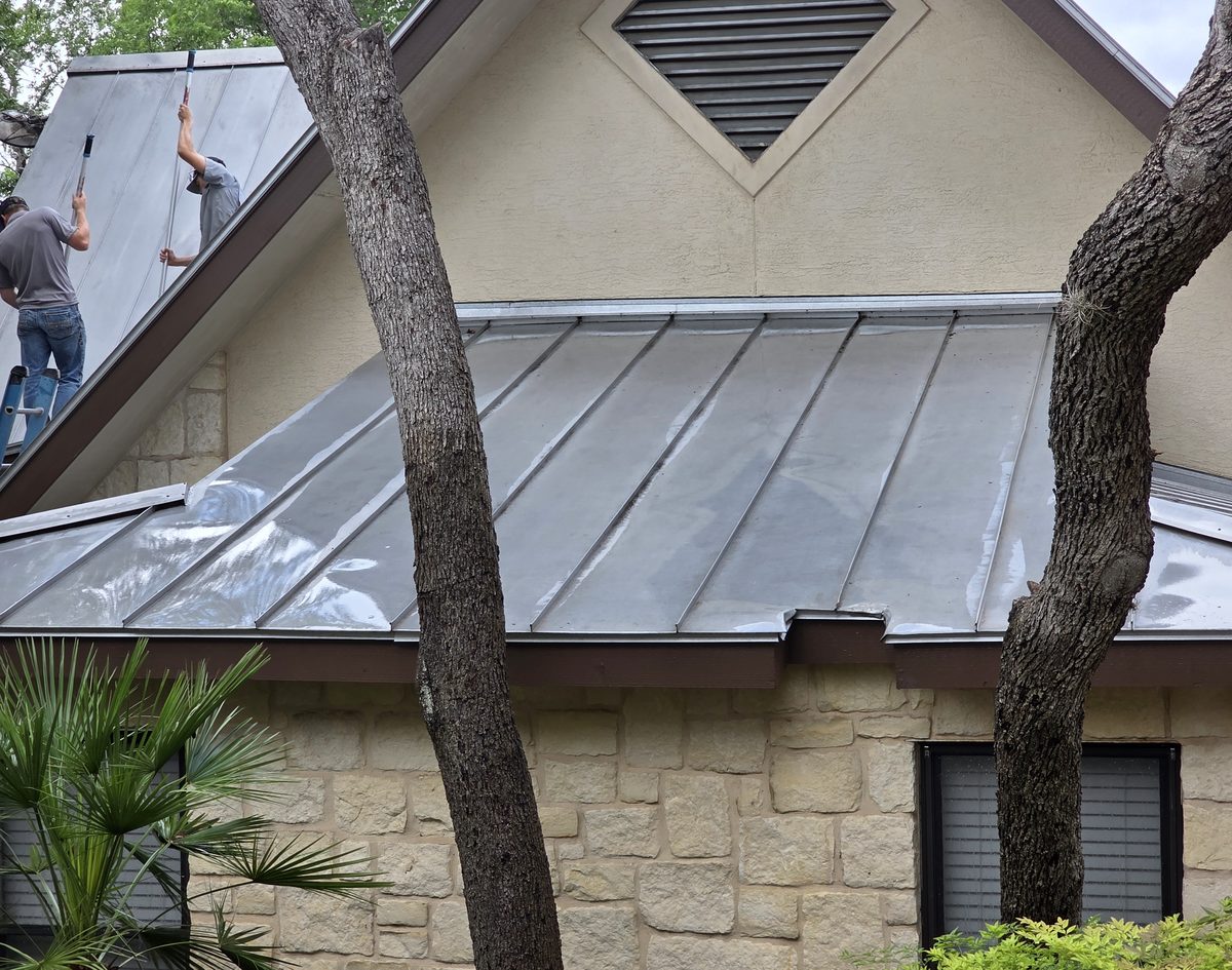 Crew working the roofline of a stone home